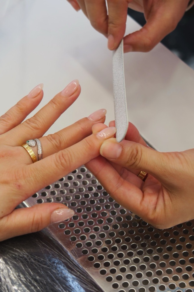 Mise en forme à la lime d’ongles longs pendant une pose en cabine