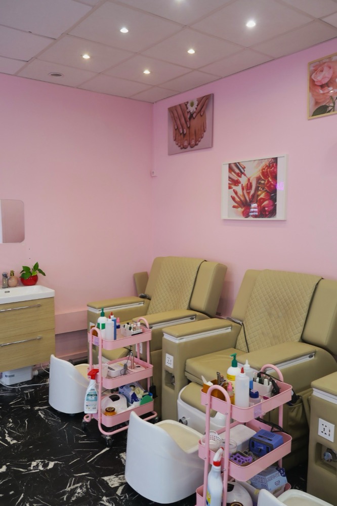 Espace pédicure du salon : deux fauteuils avec bacs, murs roses et dessertes de soins